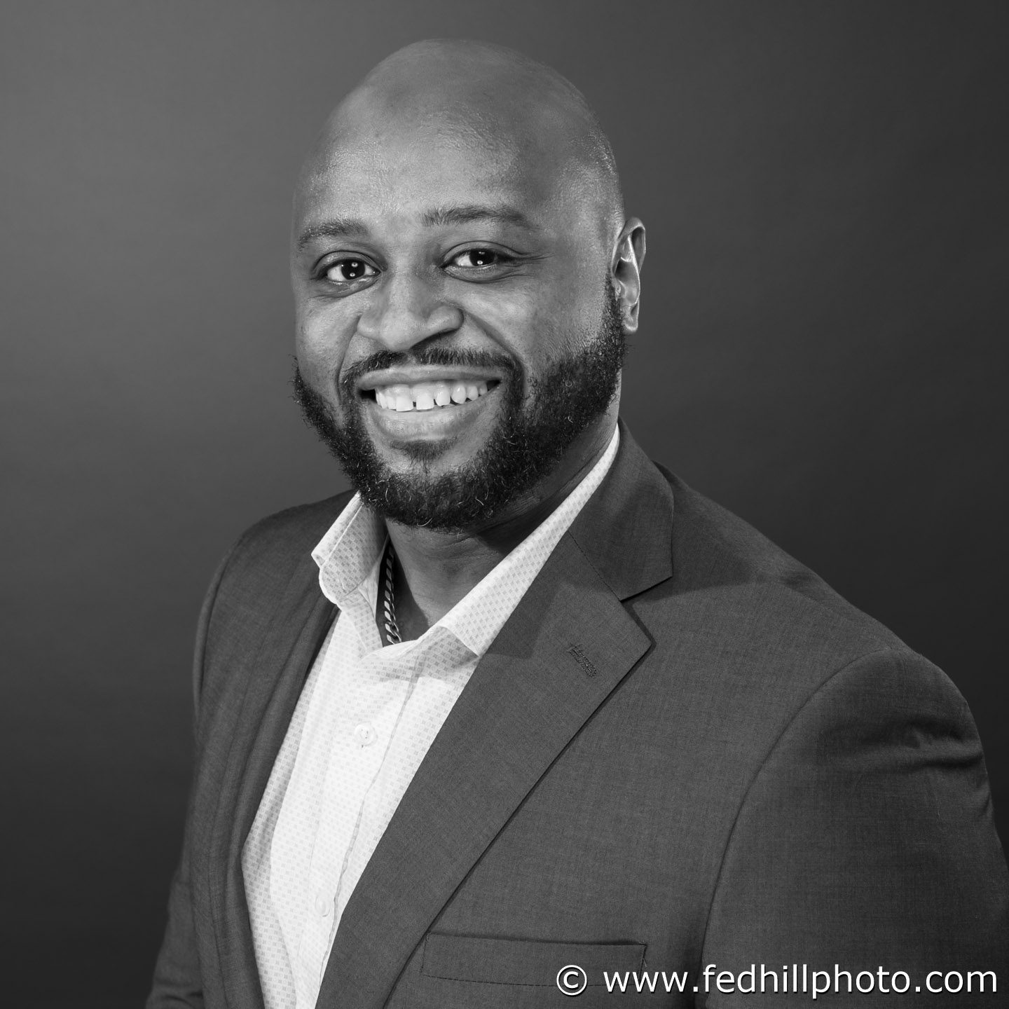 Professional black and white headshot on a solid color background.