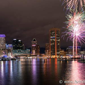 Fine art photograph of New Year's fireworks in sky and reflected in water at night in Inner Harbor, Baltimore City, Maryland.
