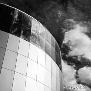 Black and white fine art photo of IMAX theater at the Maryland Science Center, Baltimore, Maryland. Sky with puffy clouds.