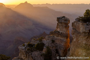 Fine art photo of rays of sunlight shining through mist and canyon rim at sunrise in Grand Canyon National Park, Arizona.