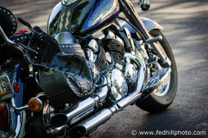 Fine art photograph of afternoon sunlight on a shiny motorcycle engine, exhaust, seat, gas tank, and wheels.