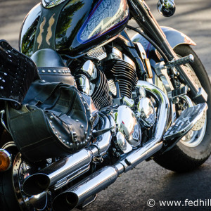 Fine art photograph of afternoon sunlight on a shiny motorcycle engine, exhaust, seat, gas tank, and wheels.