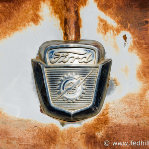 Fine art photo of rusted and decayed antique vintage Ford pickup truck hood ornament.