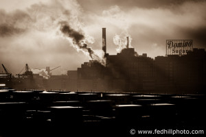 Fine art photograph of sunlight through Domino Sugar Factory steam and Pier Homes At Harbor View roofs, Baltimore City, MD.