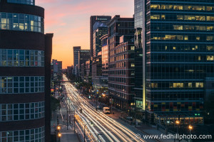 Fine art photo of Pratt St west at sunset in Baltimore City, Maryland. Car headlight streaks. Offices, apartments, condos.