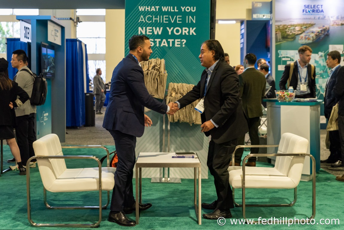 Corporate event photo of two people shaking hands at a tradeshow booth.