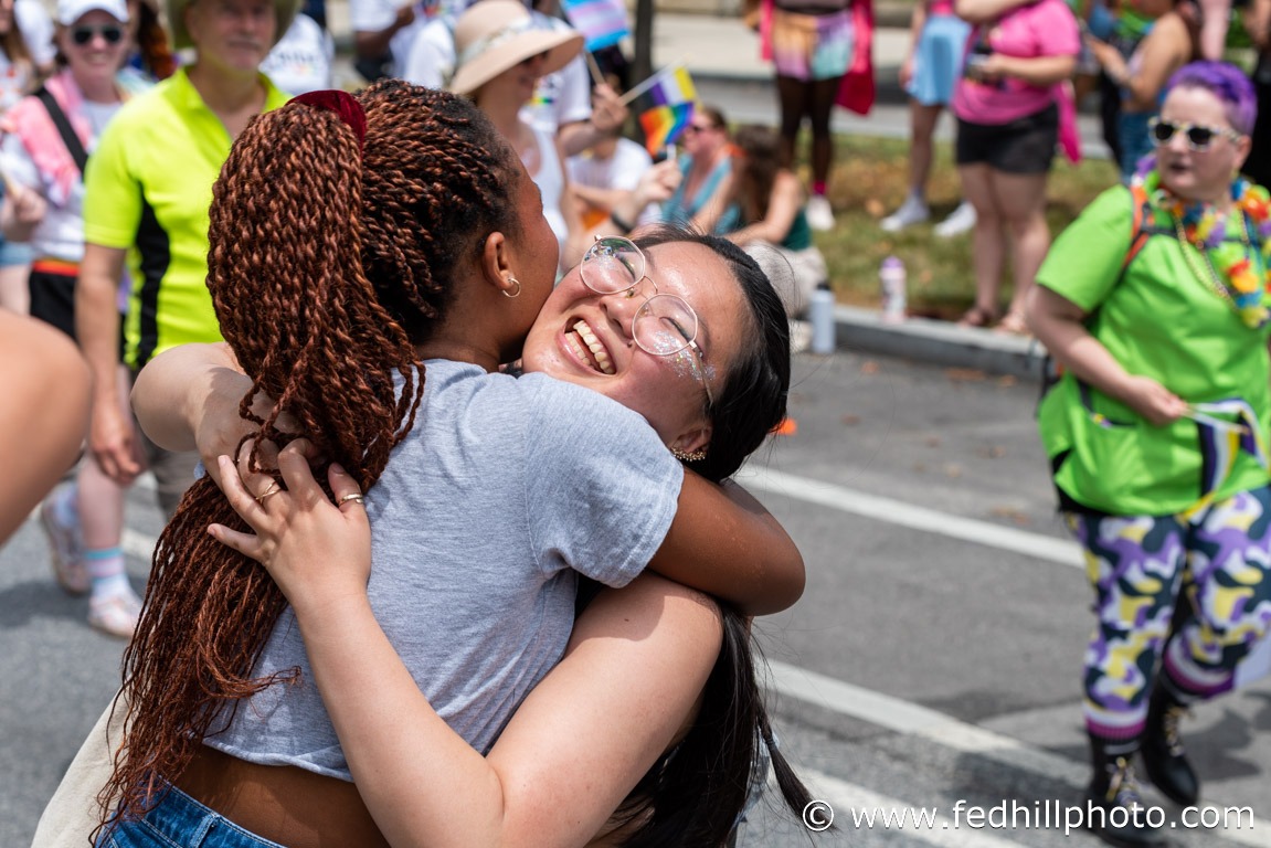 Community event photo of two people embracing during a parade.